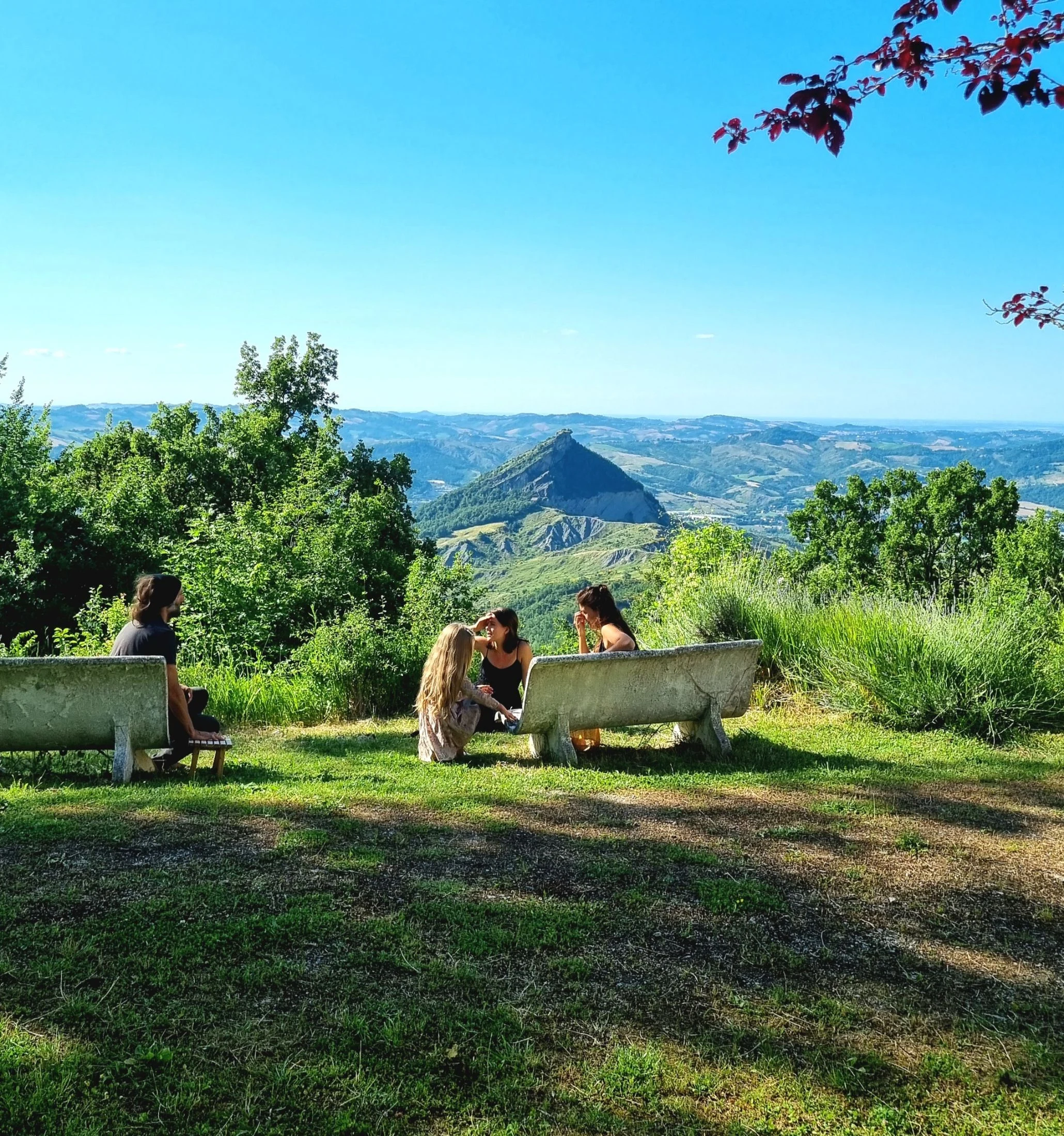 Community members talking together on the stone benches at Honeydew, overlooking the hills and a rocky peak