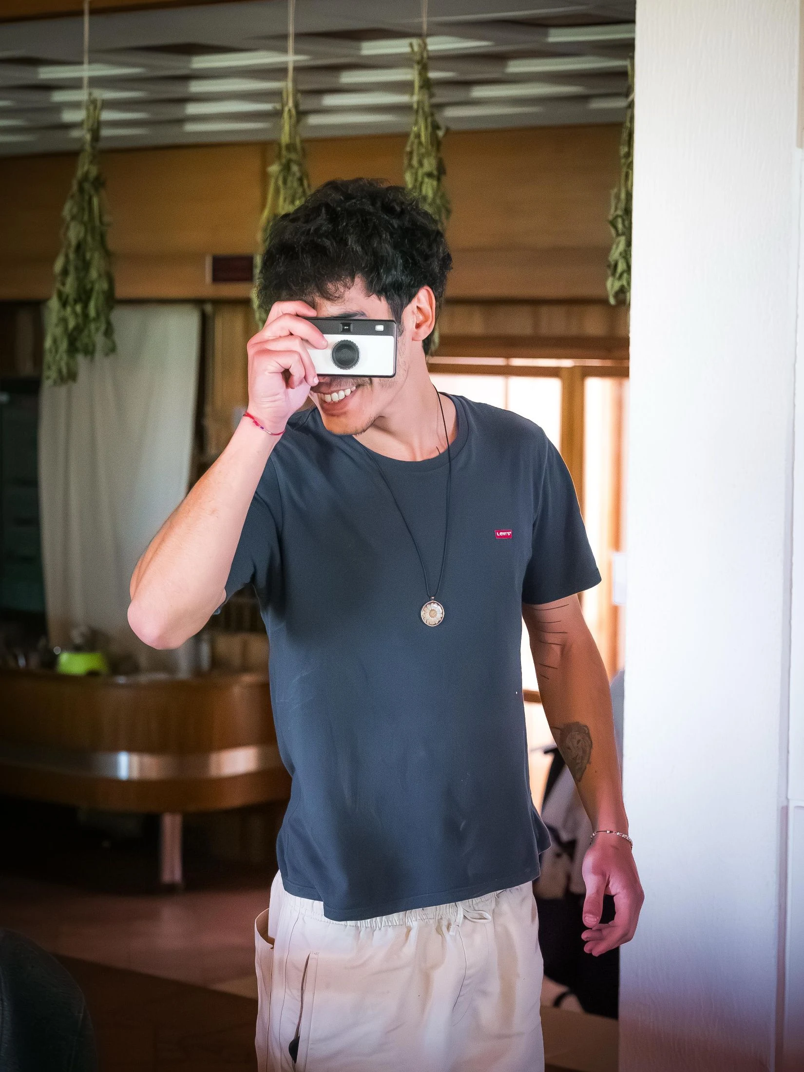 A volunteer photographing life at Honeydew in the herb-hung communal room